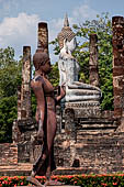 Thailand, Old Sukhothai - Wat Sa Si. Statue of a walking Buddha with the Buddha statue of the main vihan.  